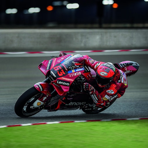 Μια κόκκινη μοτοσυκλέτα Ducati MotoGP παίρνει απότομη στροφή σε αγωνιστική πίστα