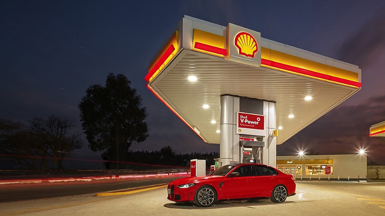 Ένα κόκκινο BWM M3 σταθμευμένο σε ένα προαύλιο της Shell κατά το σούρουπο