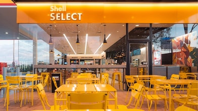 Καφέ με έντονο φωτισμό και πολύχρωμο και άνετο καθιστικό κάτω από την επωνυμία Shell Select.